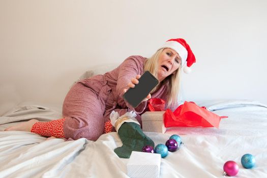 person in santa hat and bathrobe sadly shows her cell phone with nothing on it 