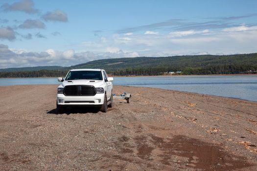 rugged pickup truck on a rocky beach beside the ocean 