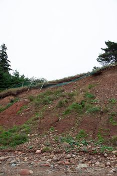 wooden fence falling off the side of an eroding cliff bank due to climate change 