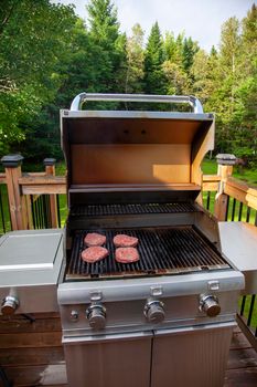 open lid on a barbeque shows hamburger cooking away 