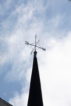  a metal weathervane showing directions on top of a steeple 