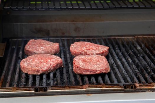 raw hamburger meat cooking on the barbeque