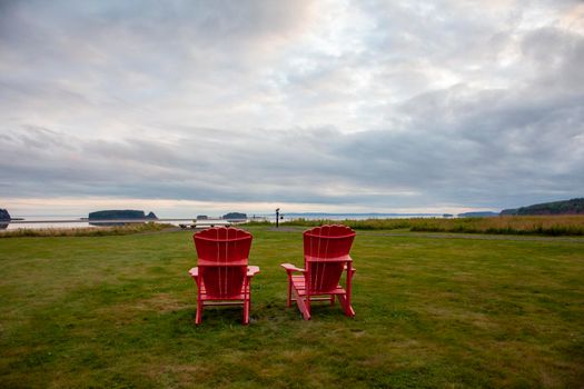 August 18, 2019 - Five Islands, Nova Scotia - two red chairs sit on a lawn by the Atlantic ocean at Five Islands, build in honour of Canada's 150th birthday 