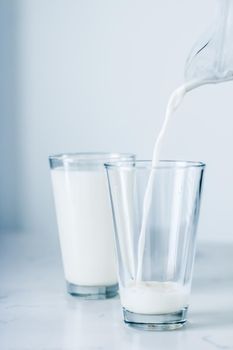 Dairy, healthy nutrition and breakfast concept - World Milk Day, pouring into glass on marble table