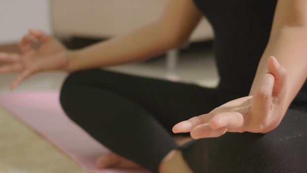 Asian young woman leggings practicing yoga at home sitting in lotus pose on yoga mat for balance, female working out at home in living room. lifestyle sport healthy meditation concept, slow motion