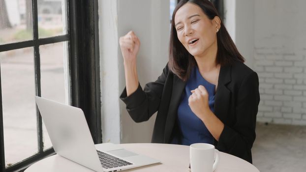 Yes! Happy excited successful, Asian businesswoman smile workstation triumphing with raised hands with laptop computer, woman success project online winner