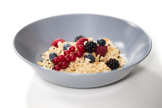 Close up of beautiful modern blue plate with appetizing oatmeal with fresh berries on white background. Concept of healthy breakfast at home for maintain body weight.