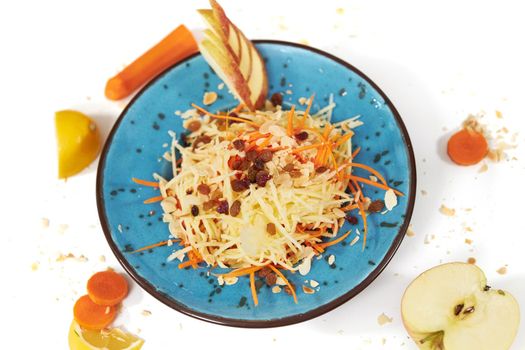 Top view of grated apple with carrots in modern beautiful blue plate on white background. Concept of proper nutrition without sugar and with healthy fruits and vegetables. 