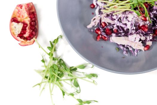 Top view close up of fresh salad purple cabbage with juicy grenade and green arugula on white background. Concept of modern delicious with healthy ingredients at home. 