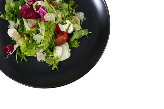 Top view close up of black modern plate with healthy fresh salad with arugula,colors leaf and juicy tomatoes on white background. Concept of proper nutrition for weight loss. 