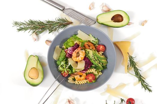 Top view of appetizing salad with pasta and with tasty shrimps and avocado in beautiful blue plate on white background. Concept of proper nutrition for maintain body weight.