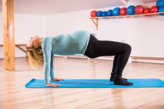 Pregnant woman enjoys exercising yoga,Setu Bandha Sarvangasana-Supported Bridge Pose