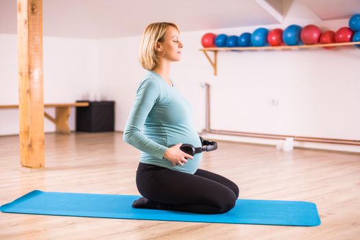 Pregnant woman playing music to her baby in gym.
