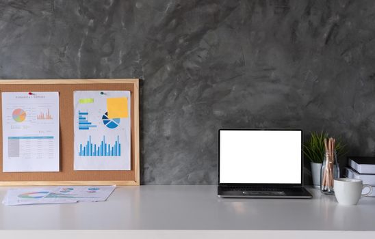 Business Workspace at home with laptop computer, financial document and office supplies on office workplace.