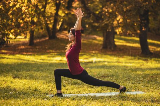 Beautiful woman doing yoga in the nature,Virabhadrasana/Warrior pose.