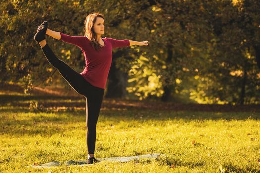 Beautiful woman doing yoga in the nature,Utthita Hasta Padangustasana /Hand to Big Toe pose