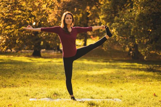 Beautiful woman doing yoga in the nature,Utthita Hasta Padangustasana /Hand to Big Toe pose