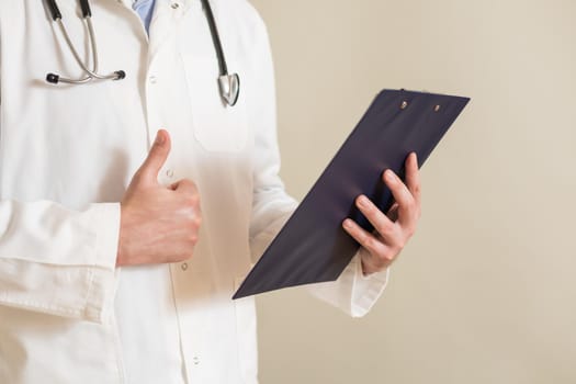 Image of male  doctor showing thumb up and holding documents.