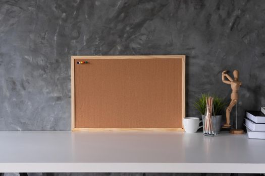 White working space with Cork board and cup, office supplies and book in home office workplace.