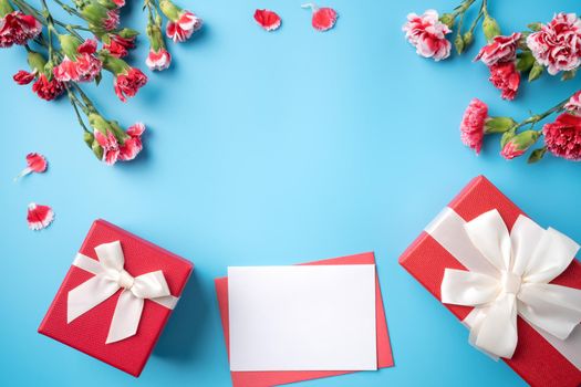 Mother's Day gift. Top view design concept of holiday greeting card with red carnation bouquet on bright blue table background