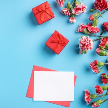 Mother's Day gift. Top view design concept of holiday greeting card with red carnation bouquet on bright blue table background
