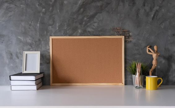 White working space with Cork board and cup, office supplies and book in home office workplace.