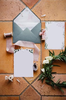 On a brown tile - an open gray envelope, blank postcards with ornaments, skeins of ribbons, a shell and a wreath of twigs with a rose. High quality photo