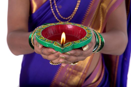 Portrait of a woman holding diya, Diwali or deepavali photo with female hands holding oil lamp during festival of light on white background