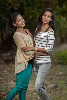 Two young girl friends standing together and having fun in outdoors. Looking at camera.