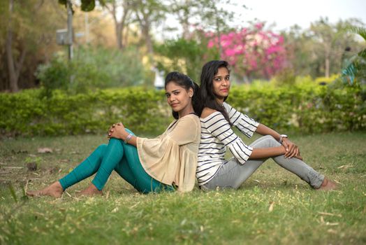 Two young girl friends having fun together in outdoors. Looking at camera.