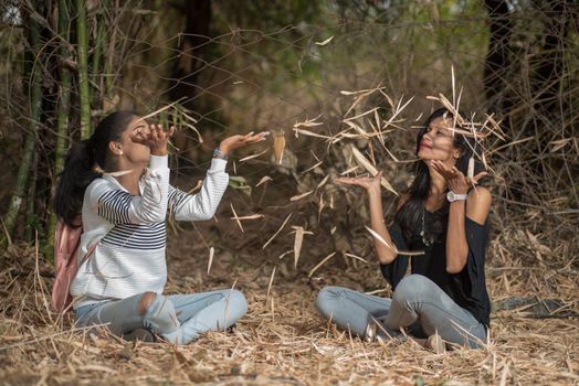 Happy girls playing with fallen leaves in park