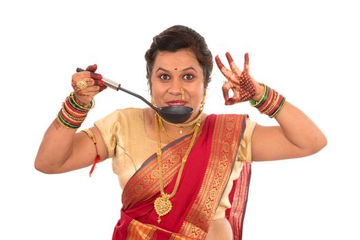 Young Traditional Indian Girl holding kitchen utensil on white background