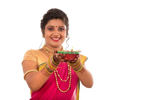 Portrait of a Indian Traditional Girl holding pooja thali with diya during festival of light on white background. Diwali or deepavali