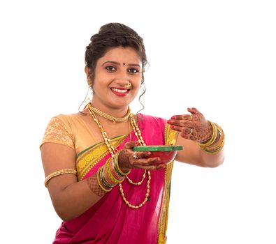 Portrait of a Indian Traditional Girl holding pooja thali with diya during festival of light on white background. Diwali or deepavali