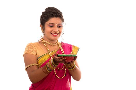 Portrait of a Indian Traditional Girl holding pooja thali with diya during festival of light on white background. Diwali or deepavali