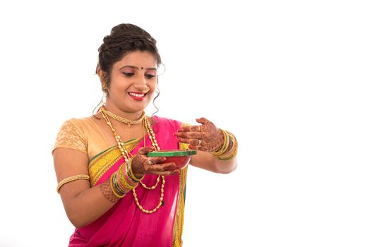 Portrait of a Indian Traditional Girl holding pooja thali with diya during festival of light on white background. Diwali or deepavali