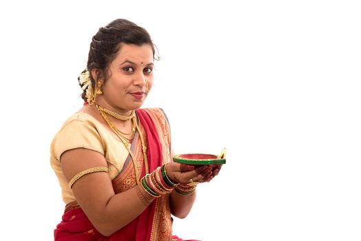 Portrait of a Indian Traditional Girl holding pooja thali with diya during festival of light on white background. Diwali or deepavali