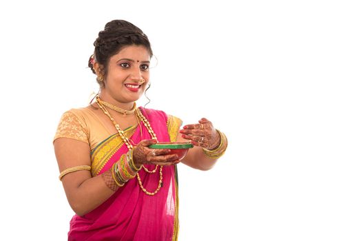 Portrait of a Indian Traditional Girl holding pooja thali with diya during festival of light on white background. Diwali or deepavali