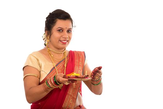 Portrait of a Indian Traditional Girl holding pooja thali with diya during festival of light on white background. Diwali or deepavali