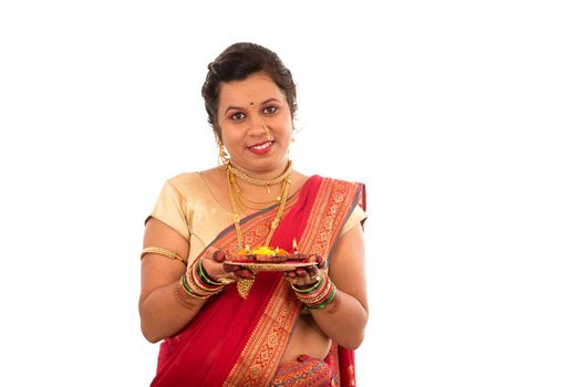 Portrait of a Indian Traditional Girl holding pooja thali with diya during festival of light on white background. Diwali or deepavali