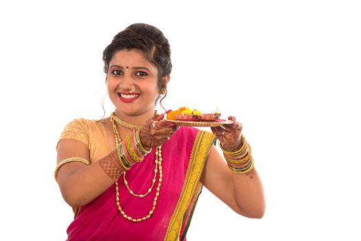 Portrait of a Indian Traditional Girl holding pooja thali with diya during festival of light on white background. Diwali or deepavali