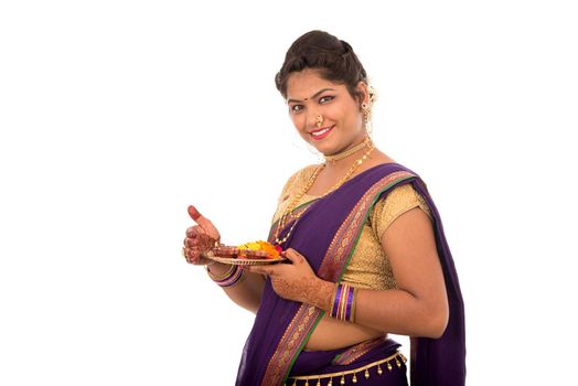 Portrait of a Indian Traditional Girl holding pooja thali with diya during festival of light on white background. Diwali or deepavali