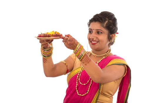 Portrait of a Indian Traditional Girl holding pooja thali with diya during festival of light on white background. Diwali or deepavali