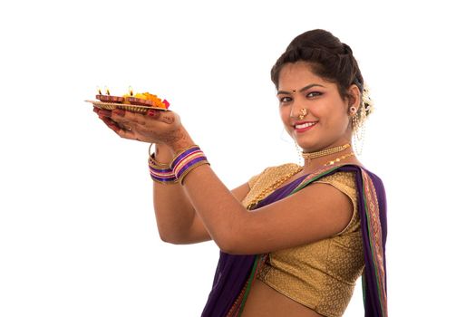 Portrait of a Indian Traditional Girl holding pooja thali with diya during festival of light on white background. Diwali or deepavali