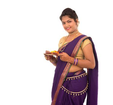 Portrait of a Indian Traditional Girl holding pooja thali with diya during festival of light on white background. Diwali or deepavali