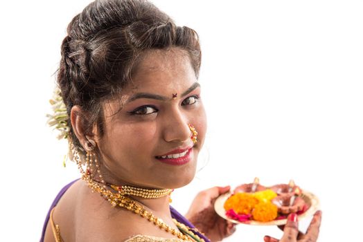 Portrait of a Indian Traditional Girl holding pooja thali with diya during festival of light on white background. Diwali or deepavali