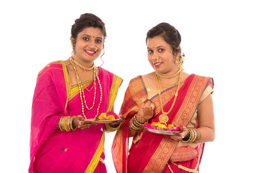 Portrait of Indian Traditional Girls holding diya and flower thali, Sisters celebrating Diwali or deepavali holding oil lamp during festival on white background