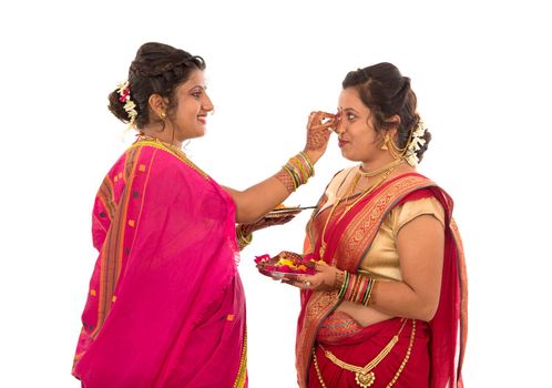 Portrait of Indian Traditional Girls holding diya and flower thali, Sisters celebrating Diwali or deepavali holding oil lamp during festival on white background