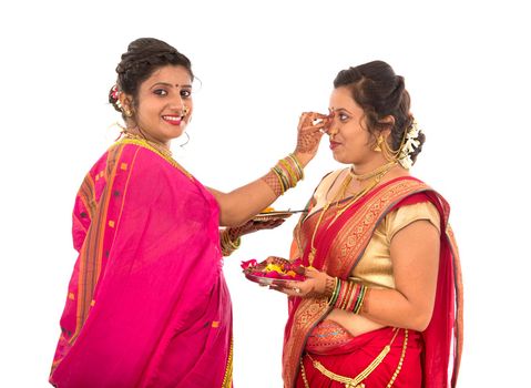 Portrait of Indian Traditional Girls holding diya and flower thali, Sisters celebrating Diwali or deepavali holding oil lamp during festival on white background