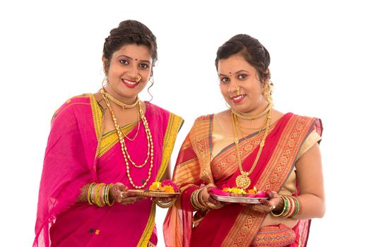 Portrait of Indian Traditional Girls holding diya and flower thali, Sisters celebrating Diwali or deepavali holding oil lamp during festival on white background